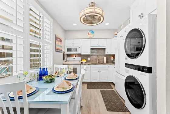 Enjoy home-cooked meals at the bright dining table just steps from the fully stocked kitchen, complete with a stacked washer/dryer for ultimate convenience.
