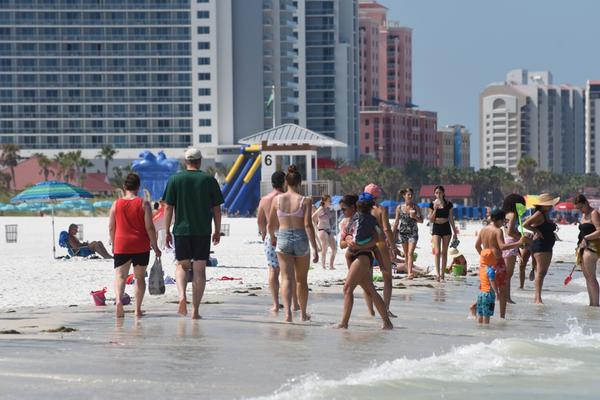 visitors to clearwater walk along the beach on a hot day