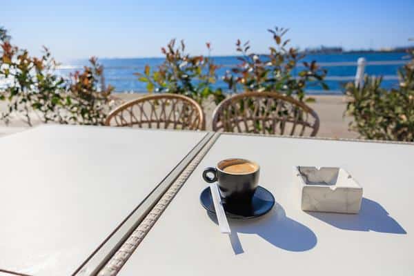 espresso cup on beachside cafe table with sea view and clear blue sky