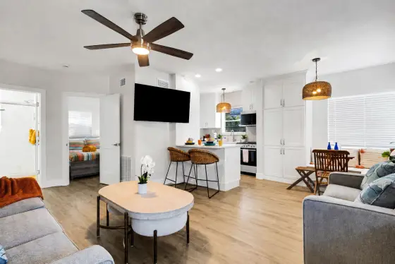 Bright, open-concept living area with plush seating, smart TV, and a cozy dining nook for four