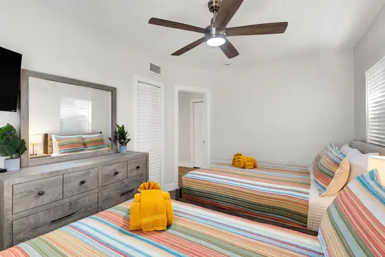 Bright bedroom with two comfortable full beds, sleeping up to four. Enjoy a smart TV, ceiling fan