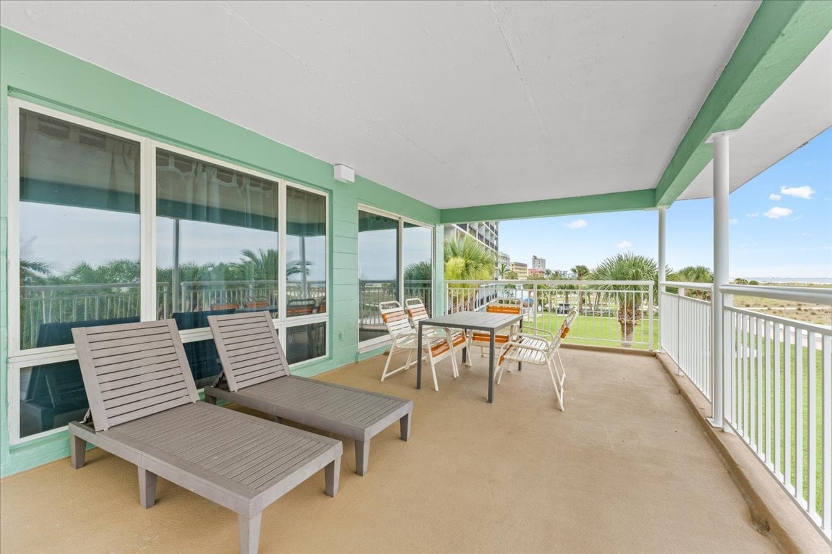 Expansive private balcony with Gulf views, lounge chairs, and a dining table for six — the ultimate spot to soak in the Treasure Island sunset.