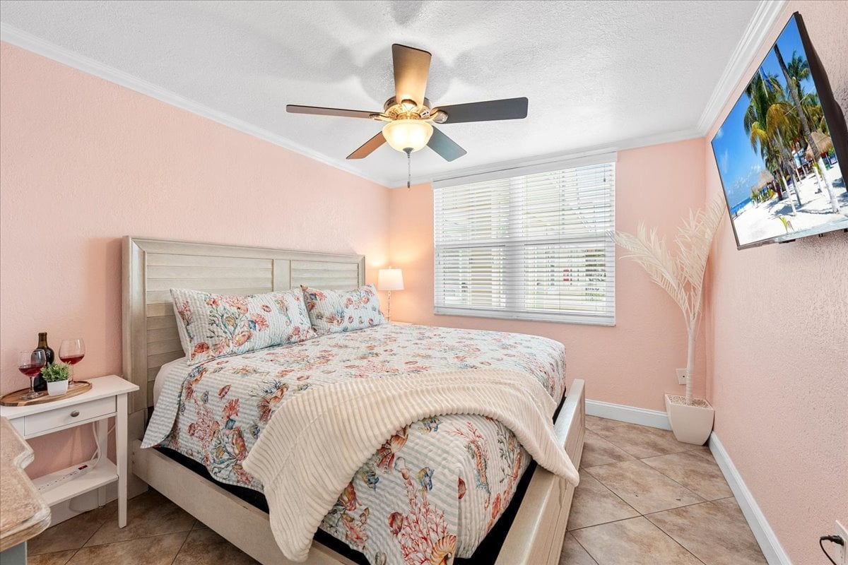 Rest easy in the spacious bedroom featuring a king-size bed, Smart TV, ceiling fan, and plenty of natural light for a relaxing coastal retreat.